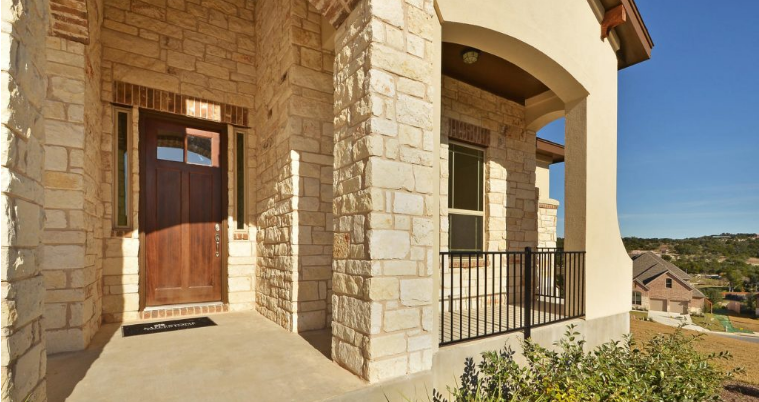 View of stone exterior and hill country from front porch of West Cypress Hills home.