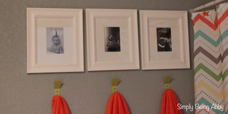 Towels on hooks below kids’ pictures in bathroom.