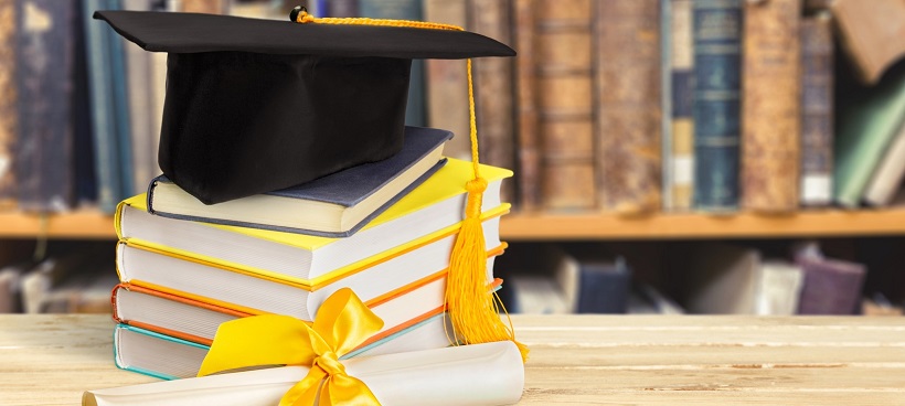 Graduation hat on top of books near diploma