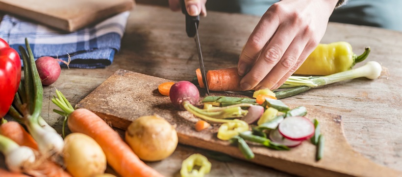 Persona cutting vegetables on cutting board.