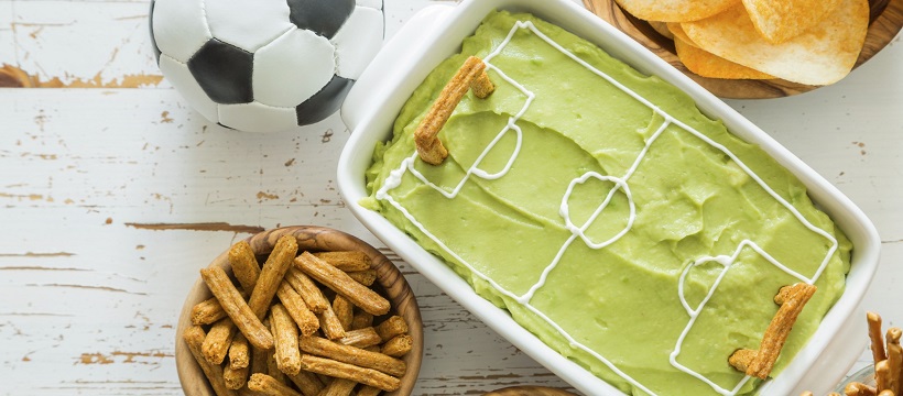 Guacamole and pretzels set out for a game day party.