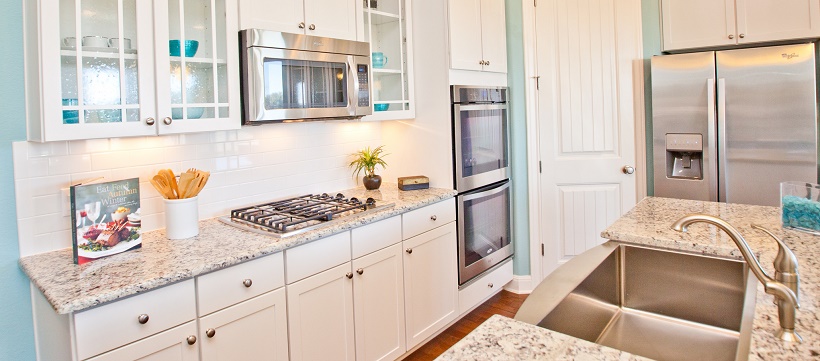 A white kitchen with blue walls, granite, and stainless steel appliances