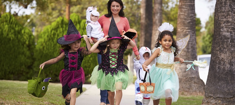 Children trick-or-treating on Halloween with an adult woman