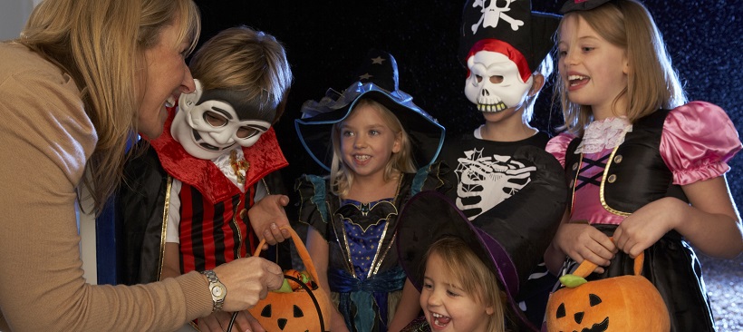 Woman handing out candy to young trick-or-treaters