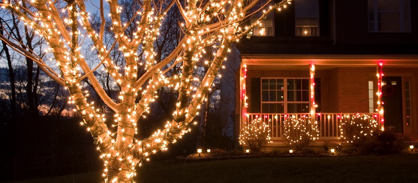 Christmas lights outside on a tree and around a porch