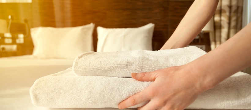 Person laying towels on bed to prepare for hosting houseguests