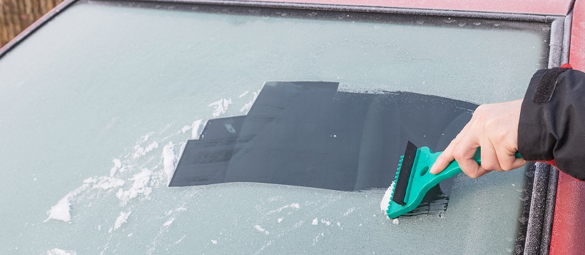 Person scraping ice of a car windshield