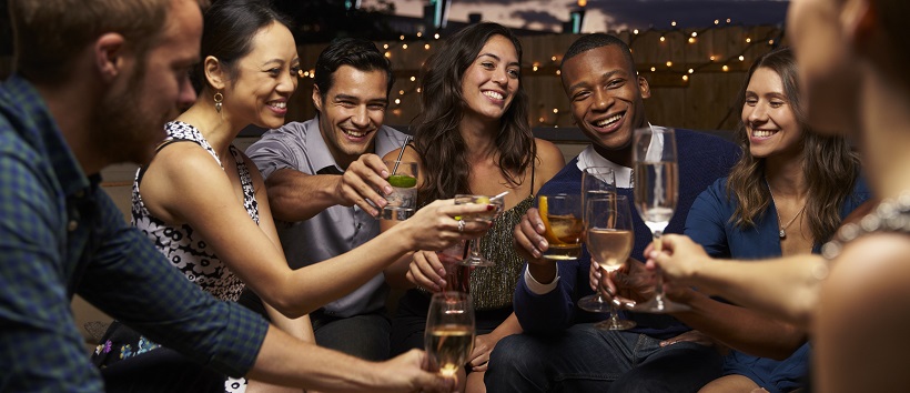 Group of younger adults enjoying downtown nightlife with drinks at a bar.