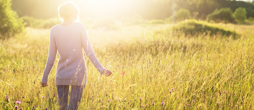 Woman standing in the middle of a field with flowers.