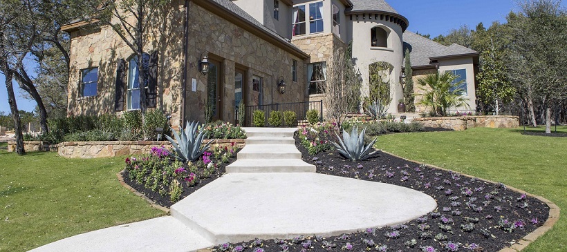 Two-story new Austin home with gorgeous landscape and stairway winding up to the front door