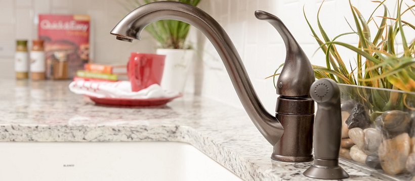 Brushed bronze faucet and white granite countertop of a kitchen in a new Austin home