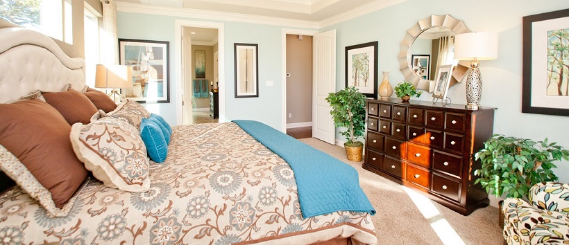 Blue walls surrounding bed with blue and brown bedspread in a new Austin home