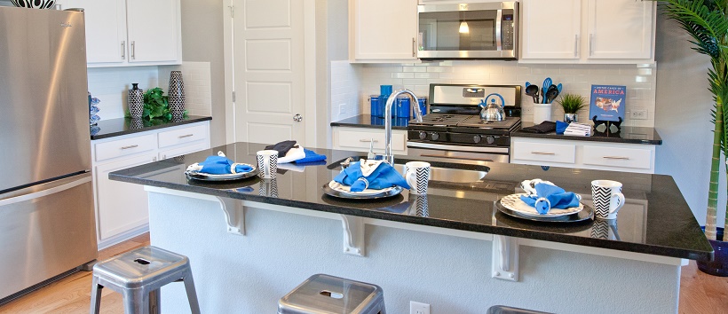 Contemporary white kitchen with blue home décor items like napkins and cooking utensils.