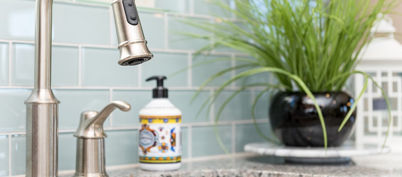 Baby blue tiled backsplash behind stainless steel faucet in kitchen.