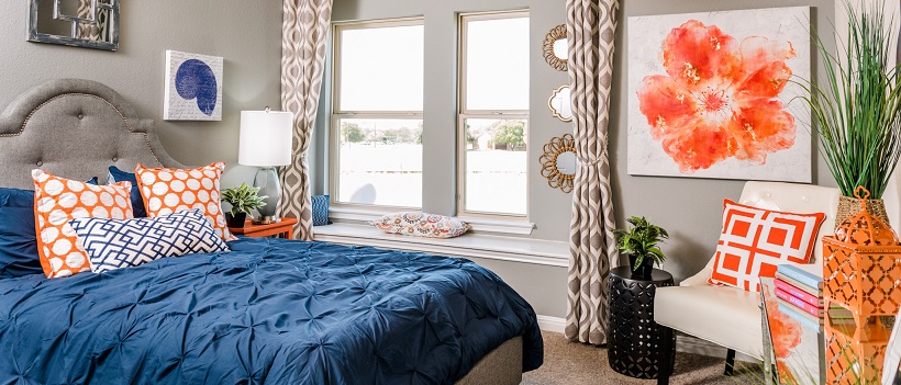 Bedroom with blue bedspread and orange and white polka dot pillows.