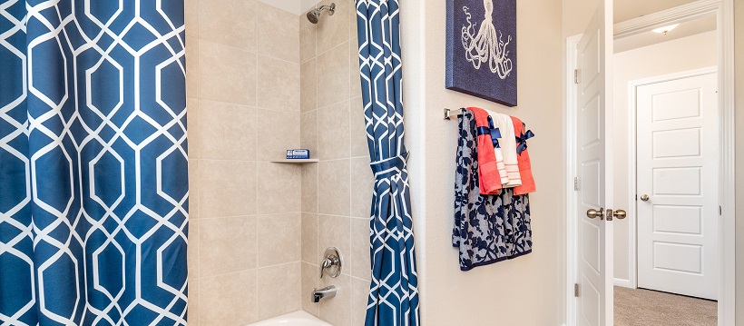 Navy blue shower curtains and navy towels and picture frame in white bathroom.