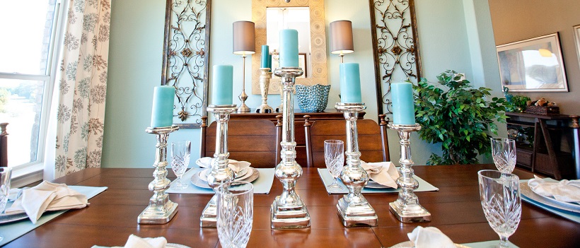 Light blue walls in dining room with wooden furniture and blue candles on candlesticks.