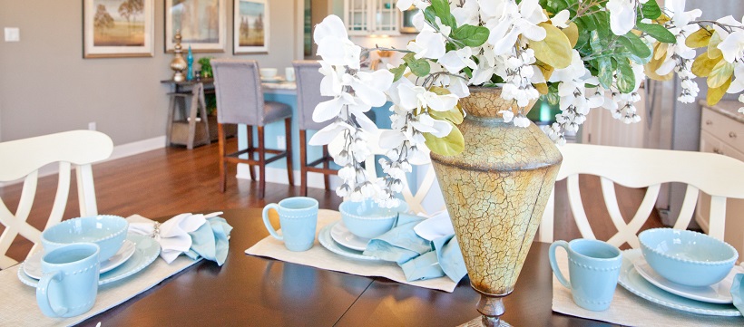 Light blue dining set around floral centerpiece on brown table in breakfast room.