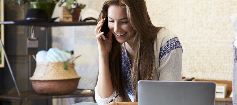 Woman researching moving timeline on laptop while calling movers on the phone.