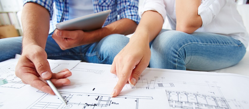 Close up of couple reviewing the floor plans to their new home as a part of their moving timeline plan.