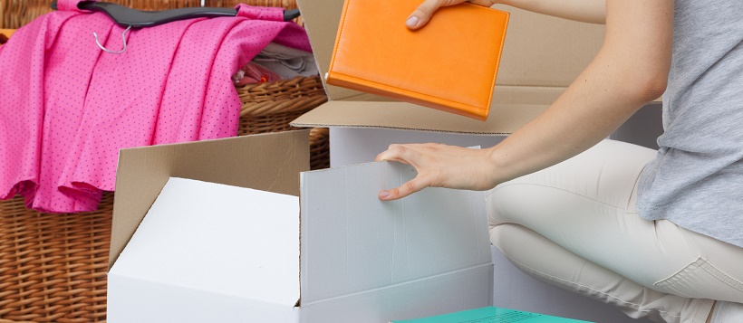 Woman working on moving timeline by packing up books and clothing.