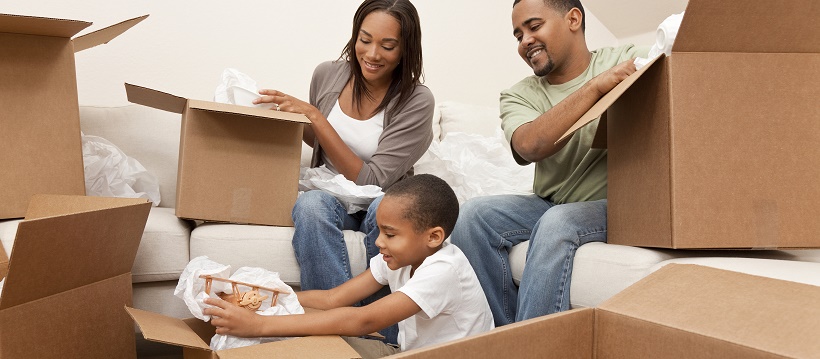 African American family packing up their home into cardboard boxes.