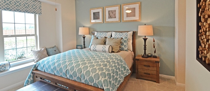 Light blue and white bedspread and pillows with light blue accent wall in South Austin home bedroom. 