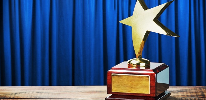 Star trophy on wooden table in front of blue curtain.