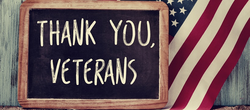 American flag hangs behind a chalkboard sign reading “Thank You, Veterans" for Austin Memorial Day events.