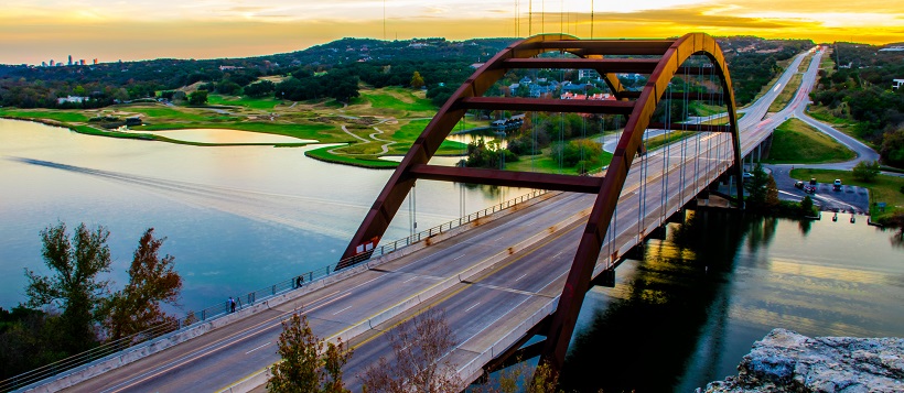 The Pennybacker Bridge over Lake Austin with orange skyline in the distance.