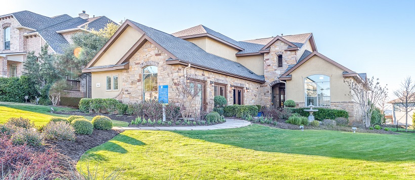 The sun sets over the landscape in front of a new home in Austin, Texas, with stucco and brick.