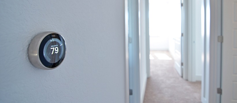 Close up of Nest thermometer on white wall of a hallway.