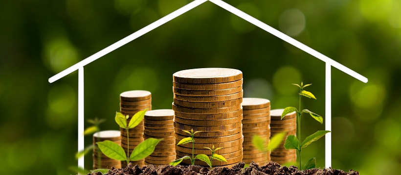 House outline over stacks of coins on soil with sprouts.