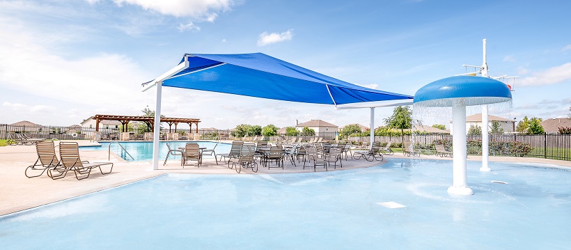 View of community center’s clean pool with play area and chairs.