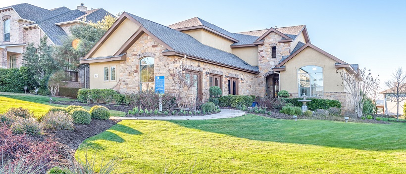 Front exterior of a two-story home with stone and stucco and a landscaped front yard.