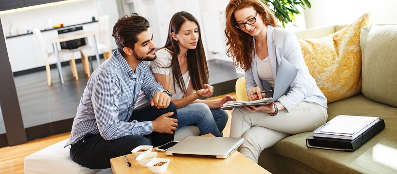 Woman realtor discussing guide to home buying with a young couple.