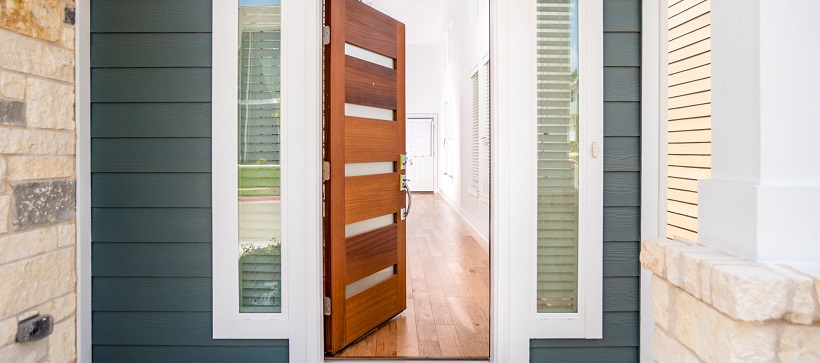 Blue siding on either side of a modern wooden door opening into a home