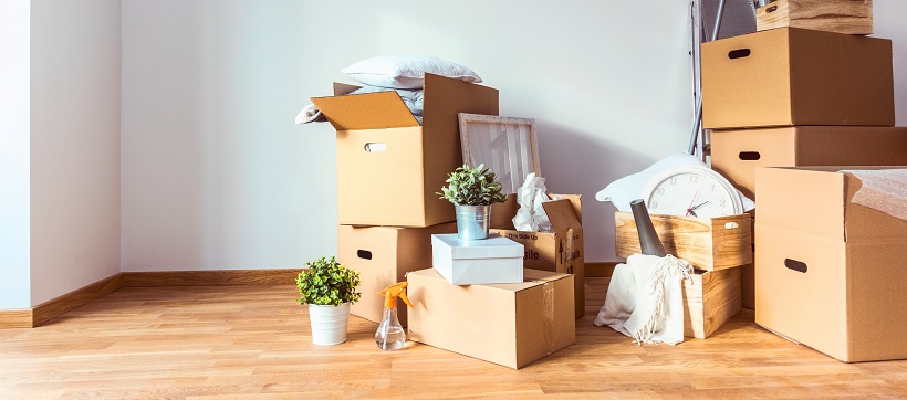 Cardboard boxes filled with items are stacked in the corner of an empty room.