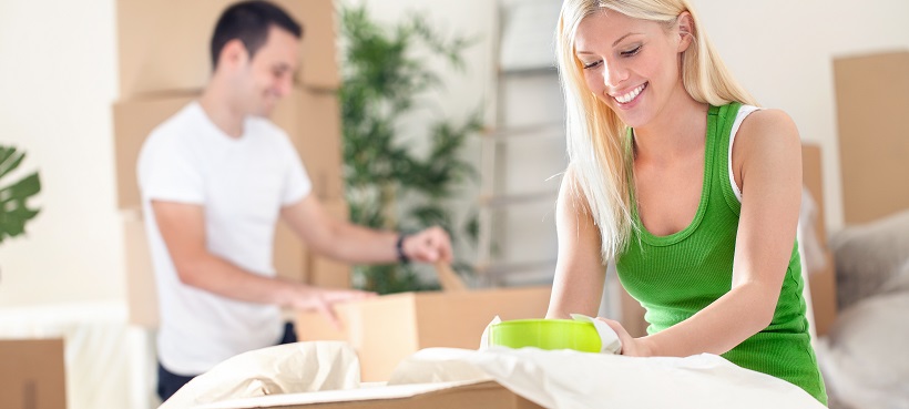 Man and woman use summer moving tips as they pack items into cardboard boxes.