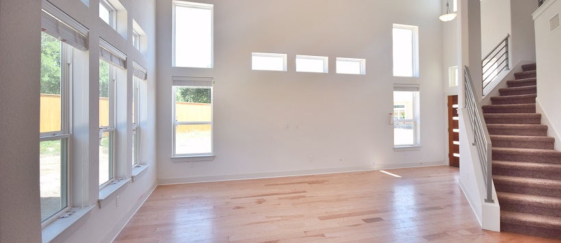 Front entry of home with staircase, light hardwood floors and white walls with various sized windows.