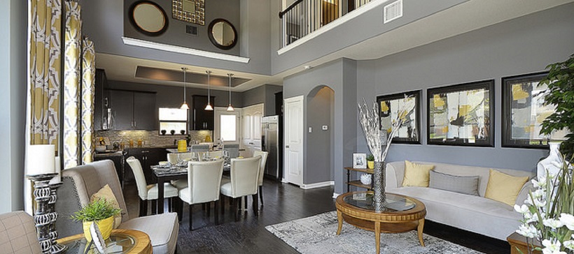 Walls with gray paint surround the living room of an open-concept home as it leads into a dining room and then the kitchen.