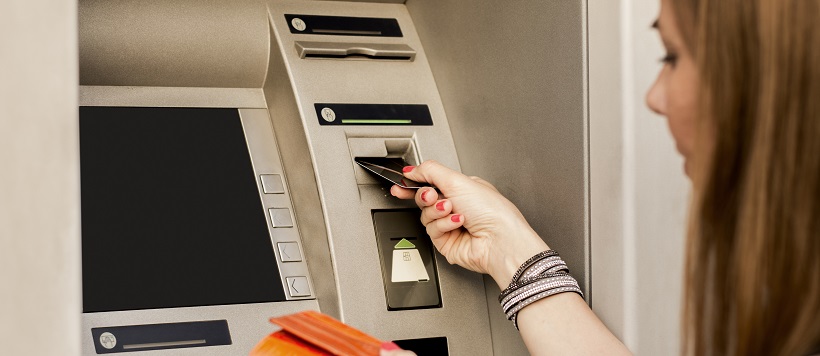 Woman putting credit card into ATM.