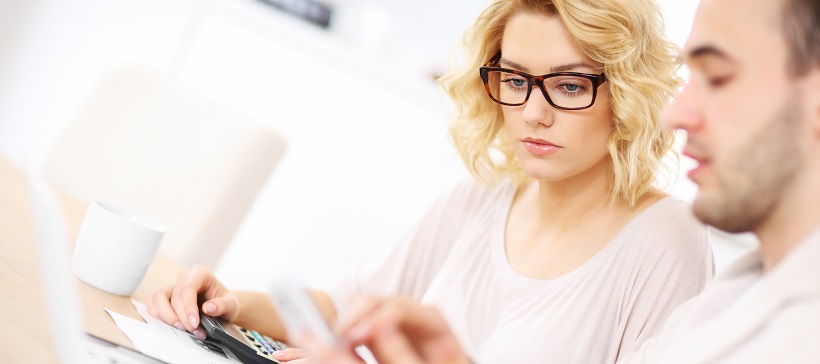 Man and woman reviewing finances with calculator to learn how to save for a home.