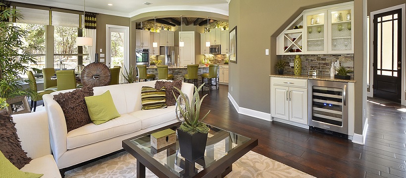 Living room with white couches and brown and yellow pillows on top of deep brown hardwood floors.