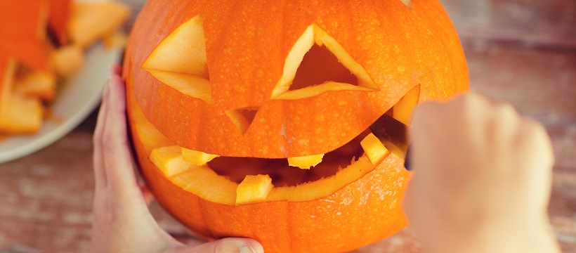 Close-up of person carving a face into a pumpkin as an outdoor entertainment idea.