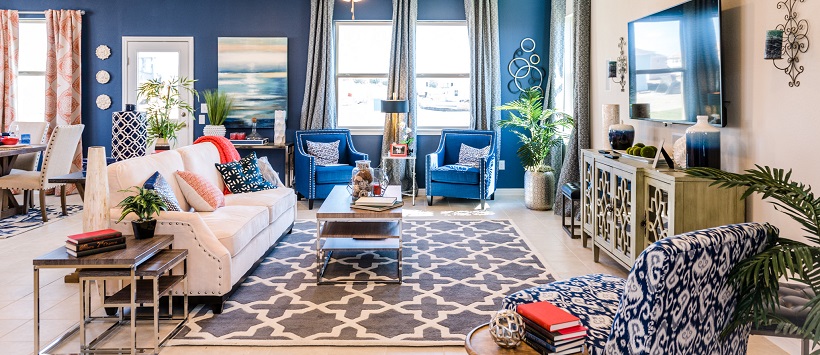 An inventory home with a vibrant living room with a blue accent wall, blue chairs, and red accent pieces.