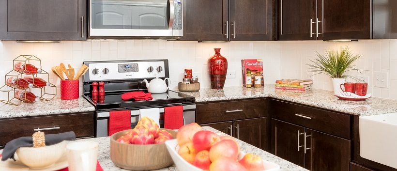 Kitchen with brown cabinetry, granite countertops and accents of red decor.