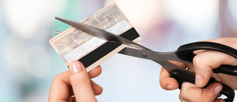 Person holding scissors and cutting credit card.