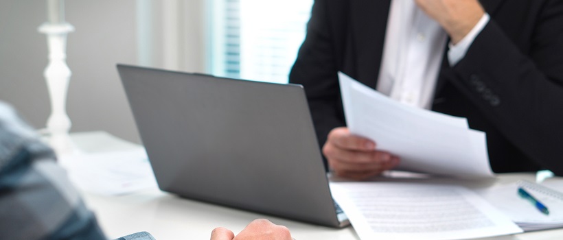 A potential homebuyer meeting with a lender who is reviewing papers.