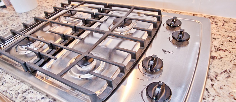 Close-up of a stainless-steel gas stovetop on a granite countertop.